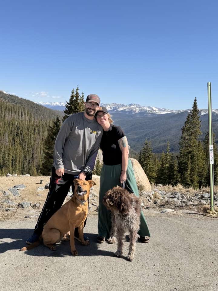 Evan Watz and Jamie Watz with their two dogs against a mountain backdrop — Jamie Watz and Evan Watz