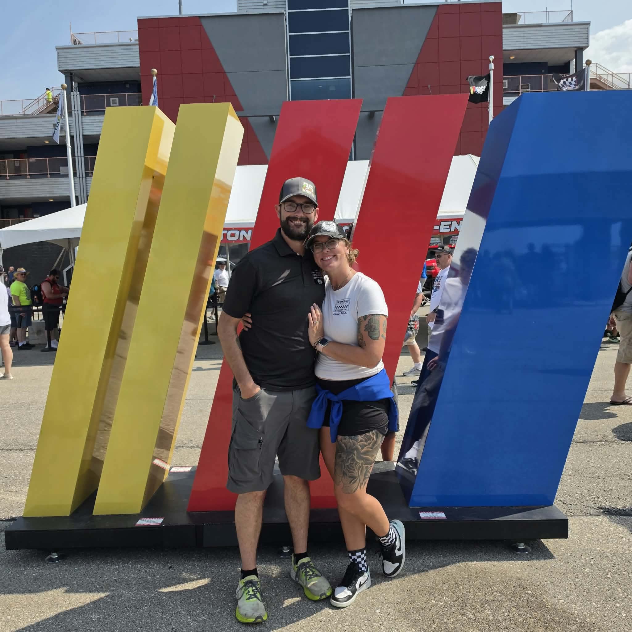 Jamie Watz and Evan Watz at the Iowa Corn 300 NASCAR race in front of a large NASCAR logo